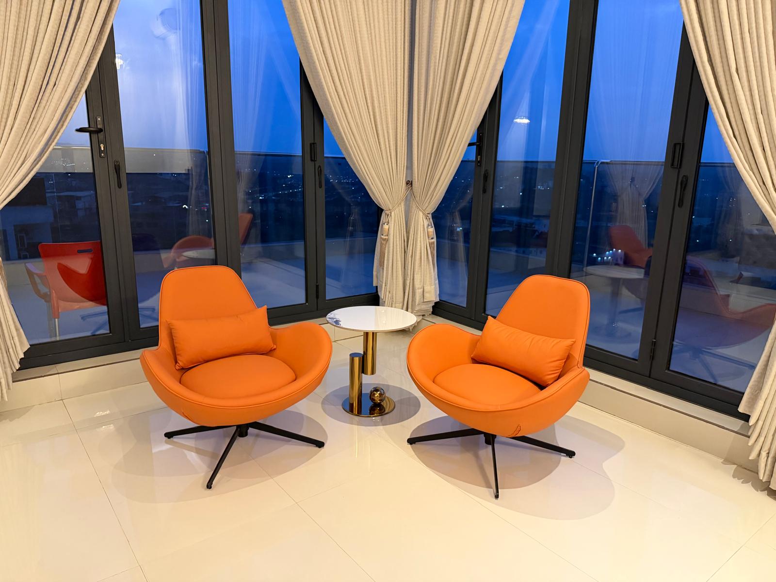 Orange lounge chairs by the balcony windows at dusk